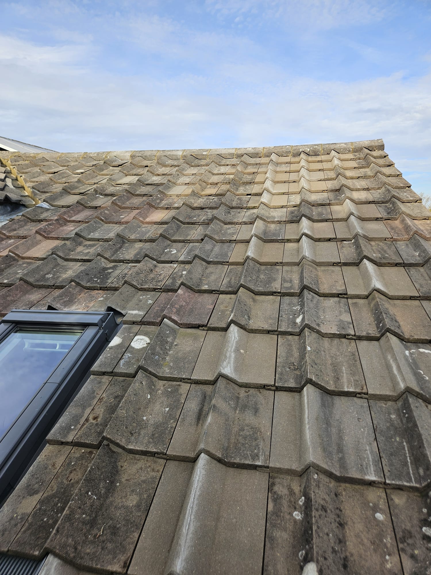 Interlocking concrete roof tiles laid in even courses on a Surrey roof slope
