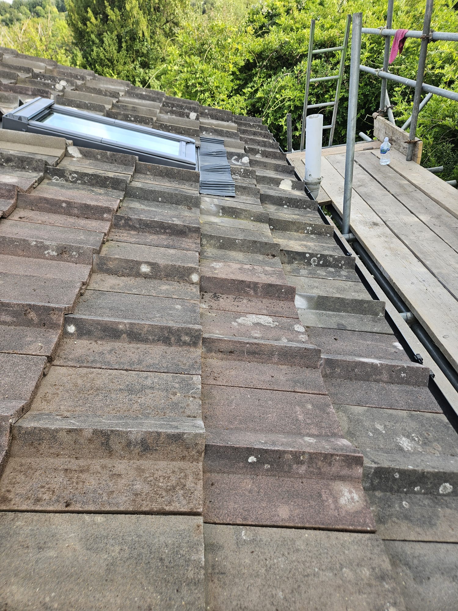 Velux roof window installation in progress with tiles set aside in Surrey