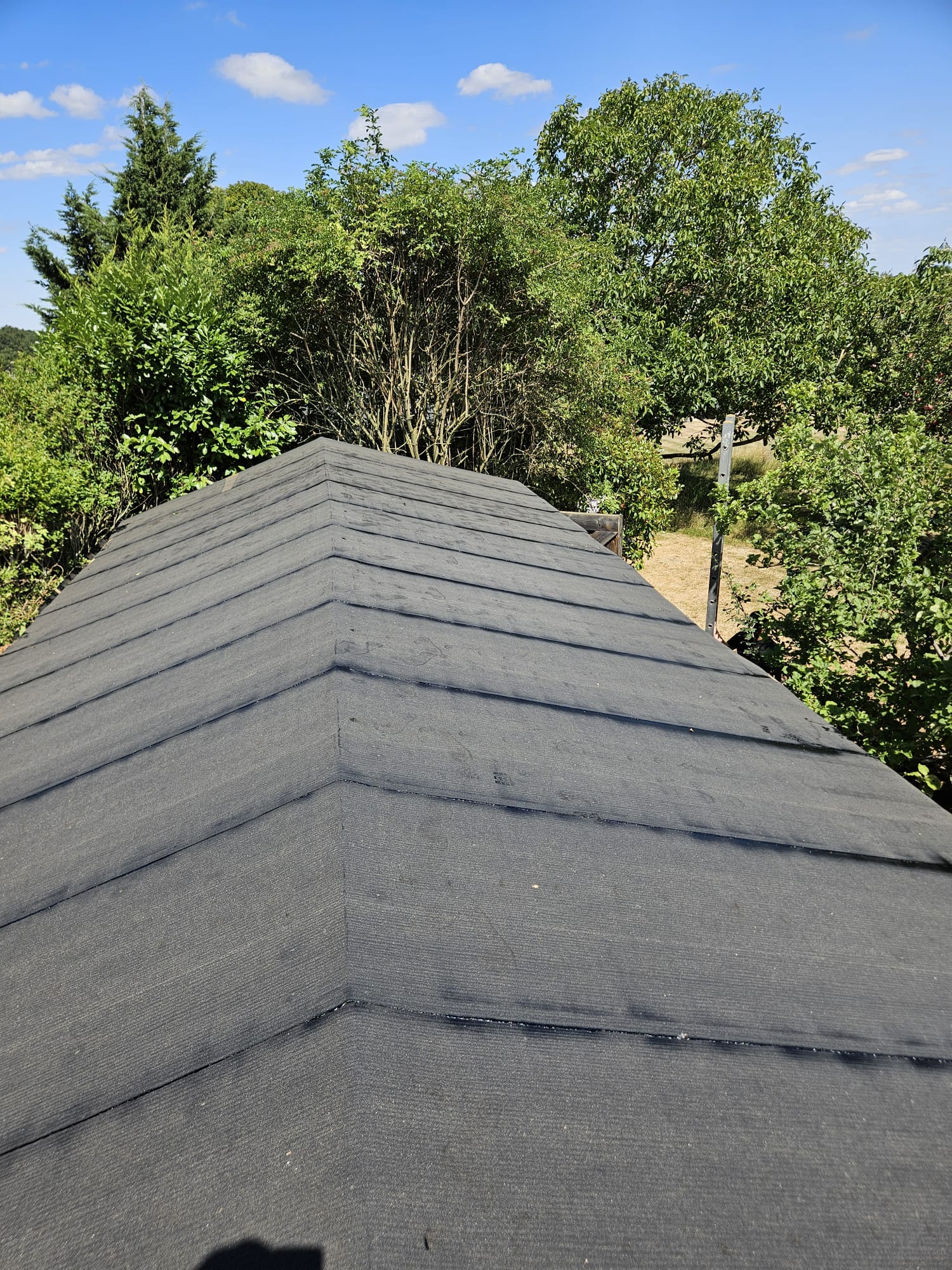 New felt roof covering completed over a Surrey outbuilding with capped hips